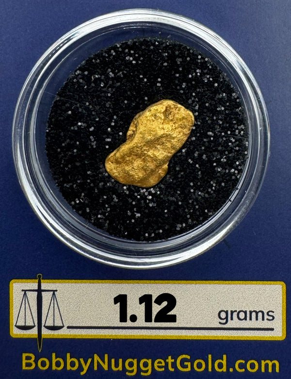 Gold nugget in a container with 'Bobby Nugget Gold' branding and weight label.