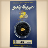 Bobby Nugget gold nugget packaging with a gold nugget inside a clear container on a blue background.