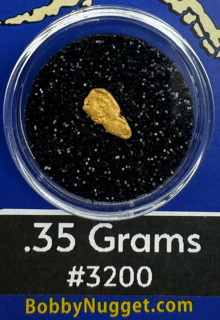 Gold nugget in a container with black sand, labeled '.35 Grams #3200' and 'BobbyNugget.com'.