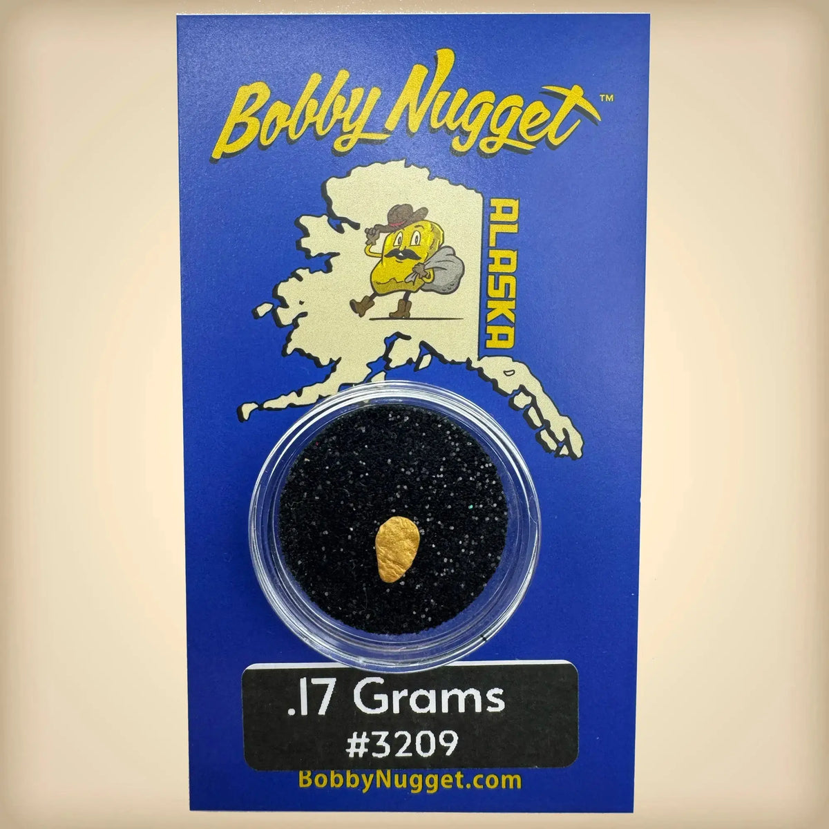 Gold nugget in a clear container on a blue card with 'Bobby Nugget' branding.