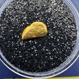 Close-up of natural California gold nugget resting on black display material inside clear case