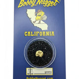 Authentic 1-gram gold nugget safely encased with a branded blue Bobby Nugget card  